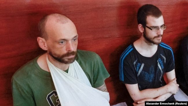 Двоє зі звільнених британців, Ендрю Хілл та Ділан Гілі, під час «суду» незаконного збройного угруповання «ДНР», серпень 2022 року