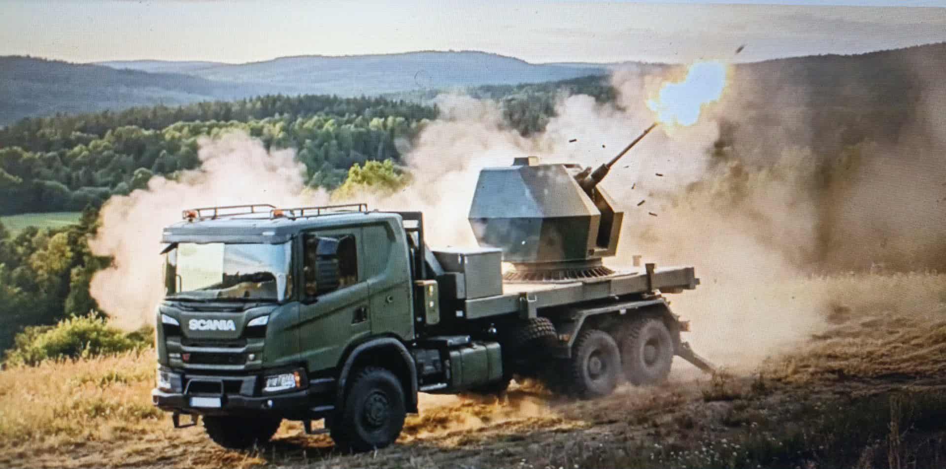Tridon MK2 – це мобільна система протиповітряної оборони середньої дальності, вона на базі вантажівки Scania веде вогонь на відкритій місцевості на тлі лісистих пагорбів під час заходу сонця.